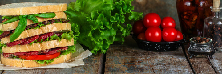 Sandwiches - bread, meat, basil, fresh leaves of lettuce on a wooden background. top view. copy space