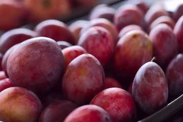 Red juicy plums. Background. Cropped snapshot. Image of fruits in a store or at a buffet. Concept of proper nutrition.
