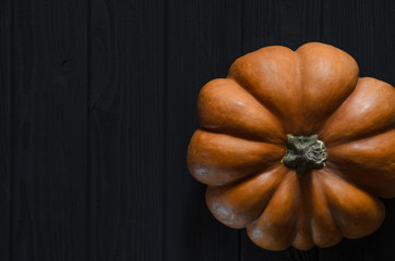 Orange texture pumpkin rests on the wood background black color
