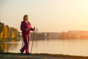 Active senior woman hiking walks at colorful Sunny autumn park