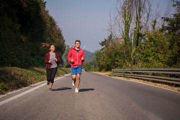 young couple jogging along a country road