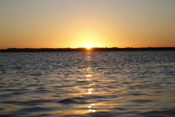 Awesome sunset in front of the beach with clean blue sky and sun