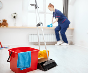 Selective focus of cleaning set for different surfaces in house with blurred image of young...