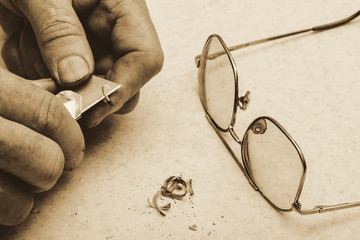 Table composition with glasses, pencil shavings and hands of elderly man who sharpens pencil with...