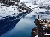 Hiker standing on edge of rock looking at lake