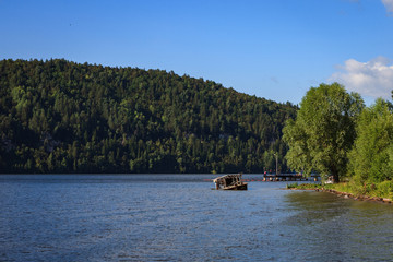 Summer sunny landscape on the river with a wreck boat