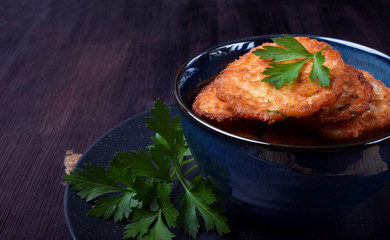 Vegetable pancakes topped with parsley leaves in a blue bowl