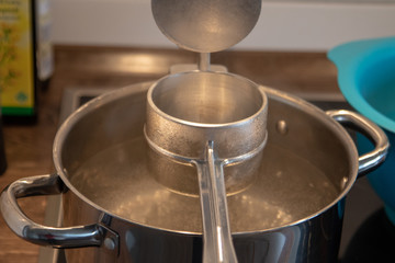 ricer for swabian spaetzle over a pot full of boiling water