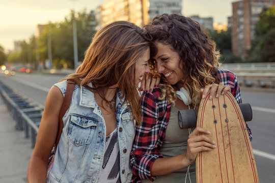Two girls in love with skateboard on hand at street