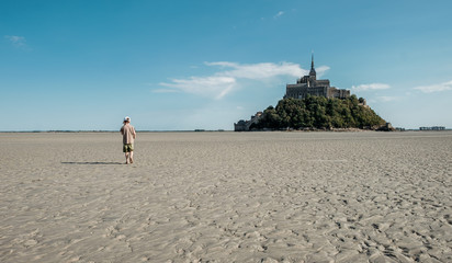 Boy walking in the bay of Mont Saint-Michel at low tide