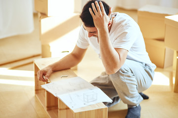Frustrated man reading instruction and assembly furniture. DIY, new home