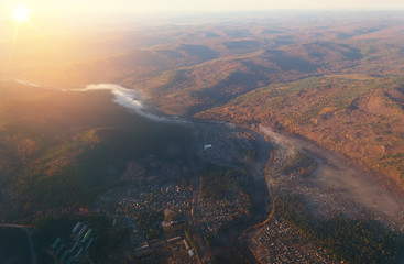 view from the window of the plane to the river with rising fog among the mountains covered with forest