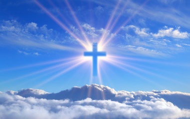 religious cross over cumulus clouds illuminated by the rays of holy radiance, concept