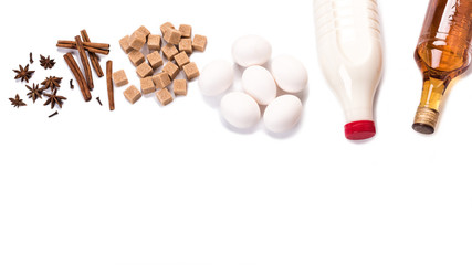 Ingredients for Christmas eggnog isolated on white background. Eggs, milk, cinnamon stick, anise stars, a bottle of rum. Flat lay, top view, copy space for recipes