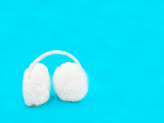 white winter headphones for the ears on a blue background . MINIMAL COMPOSITION 