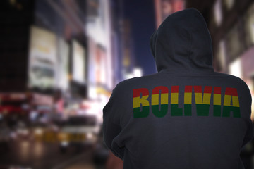 dangerous man standing on a city street with black hoodie with text bolivia on his back