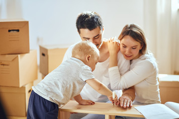 Couple with little boy assembly furniture after moving in new home