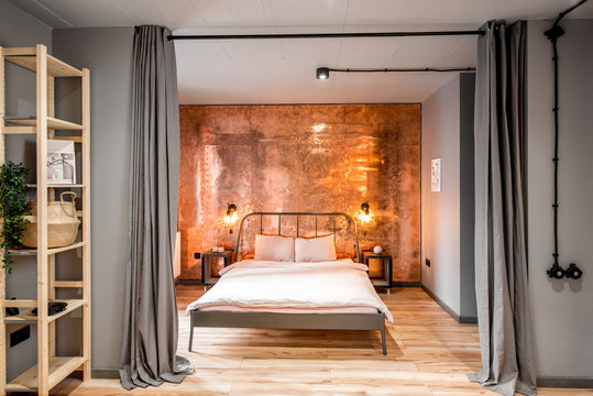 Modern loft bedroom interior with wall made of copper metal. Real photography