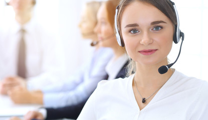 Call center. Group of operators at work. Focus at blonde business woman in headset