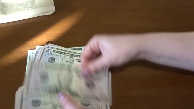 Counting a bunch of fifty dollar bills by female hands