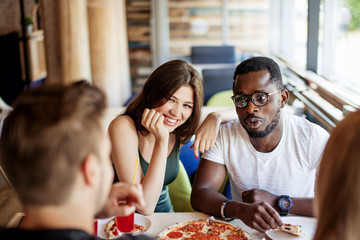 Multiracial young friends gathering for celebrating b-day of their afro american friend. Cheerful...