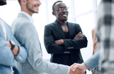 group of young people in the office.two businessmen shake hands