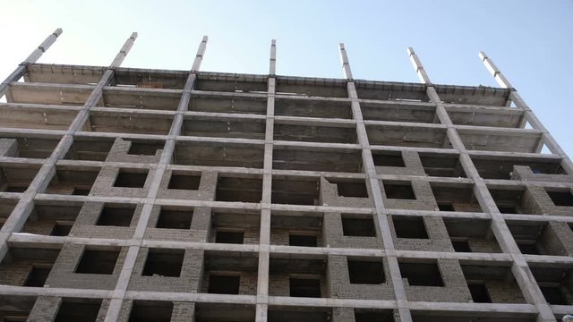 Multi-storey residential building under construction. Front view, camera moving from left to right.