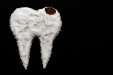 tooth made of sugar on a black background with caries