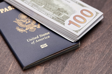 Fototapeta premium Passport of United States of American. Traveling passport. closeup of an american passport and money on a wooden table for a travel concept.