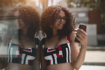 Portrait of charming caucasian girl in eyeglasses and with bulky curly hair, she is leaning against...