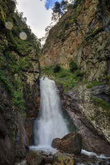 Obraz premium Waterfall on the rocky slopes of the Caucasus Mountains in Russia.