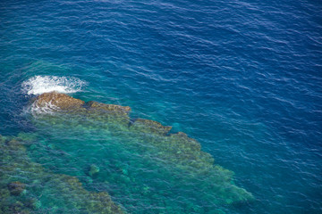 Blue water with rocks underwater in aerial view