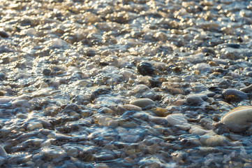 pebble stones on the sea beach, the rolling waves of the sea with foam