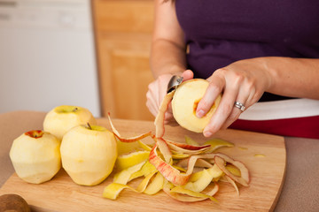 Young Woman Peeling Apples in Kitchen at Home
