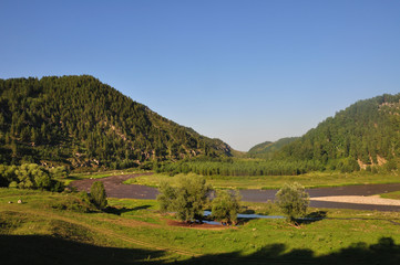 Green mountains, field, trees, clouds and blue sky.