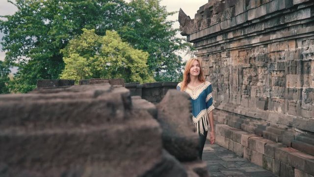 Young caucasian woman walking and smiling on middle level of Borobudur temple in Java, Indonesia