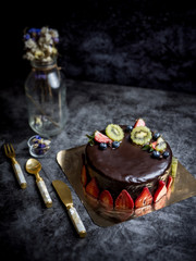 sweet pastry dessert chocolate cake with strawberry, kiwi and blueberry set on kitchen table.