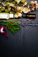 Rose flower petals and lavender herb flowers with aromatherapy glass bottles isolated over wooden background. Lavandula and rosa rugosa.