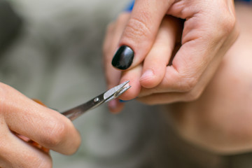 Cutting nails to a child. Female hands hold nail scissors and child's hand.