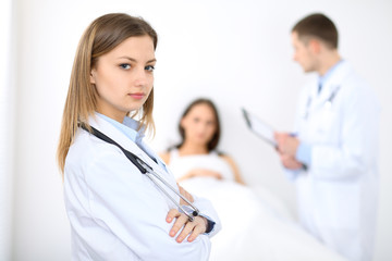 Fototapeta premium Medicine doctor standing and smiling on the background with patient in the bed