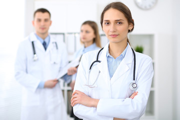 Fototapeta premium Young beautiful female doctor smiling on the background with patient in hospital