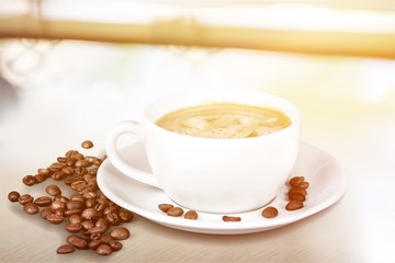 Coffee cup and coffee beans on wooden background