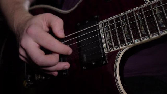 man is sitting and playing the guitar in a dark room. Close up. 4K