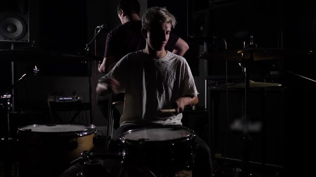 young man playing a drum set in a dark room. 4K slow motion
