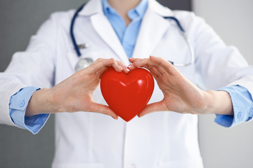 Female doctor with stethoscope holding heart in her arms. Healthcare and cardiology concept  in...