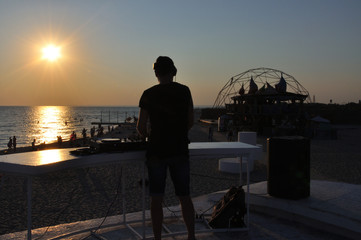 DJ plays music on the beach at sunset