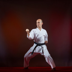 Athlete trains formal karate exercises on a dark background.
