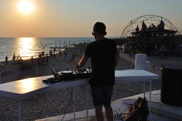 DJ plays music on the beach at sunset