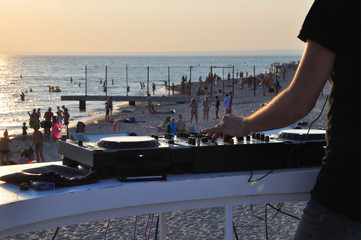 DJ plays music on the beach at sunset