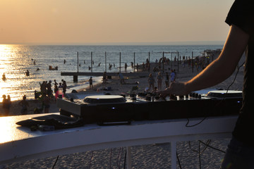 DJ plays music on the beach at sunset